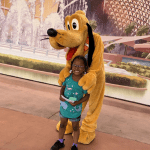 Girl with cerebral palsy smiling with Goofy from Disney World