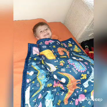 Boy with hearing loss under a weighted blanket