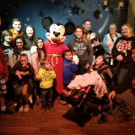 Girl in wheelchair with Mickey Mouse and her family