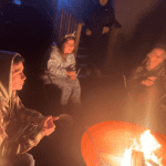 Teens sitting around a campfire and smiling