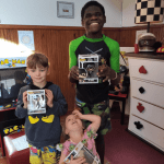 Three children holding POP figures they received during their stay at the Dream Village.
