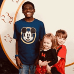 Three children smiling before entering a restaurant at Disney World.