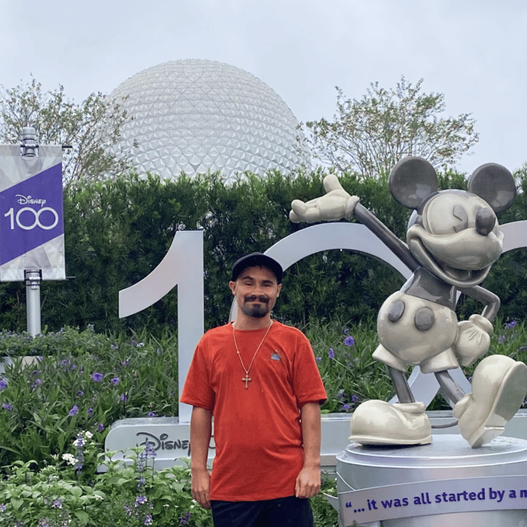 Casey with a chromosomal abnormality in front of a Mickey statue in Epcot